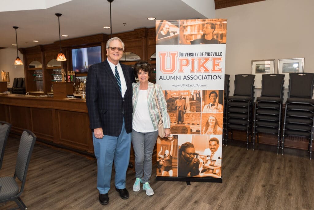 couple taking a photo in front of the UPIKE banner