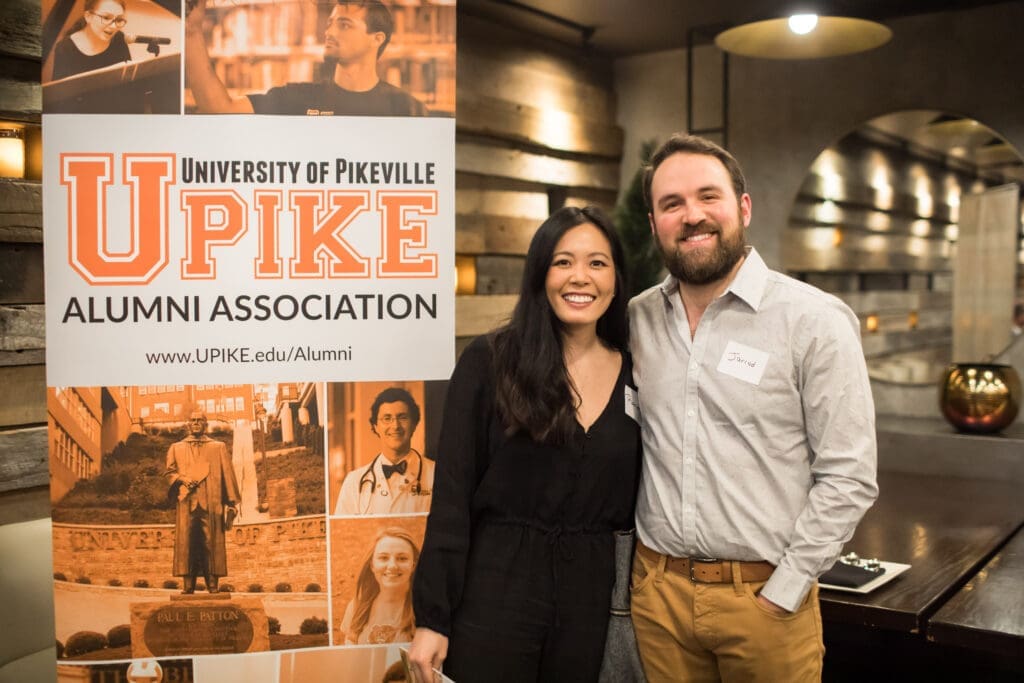 Two guests pose in front of UPIKE banner