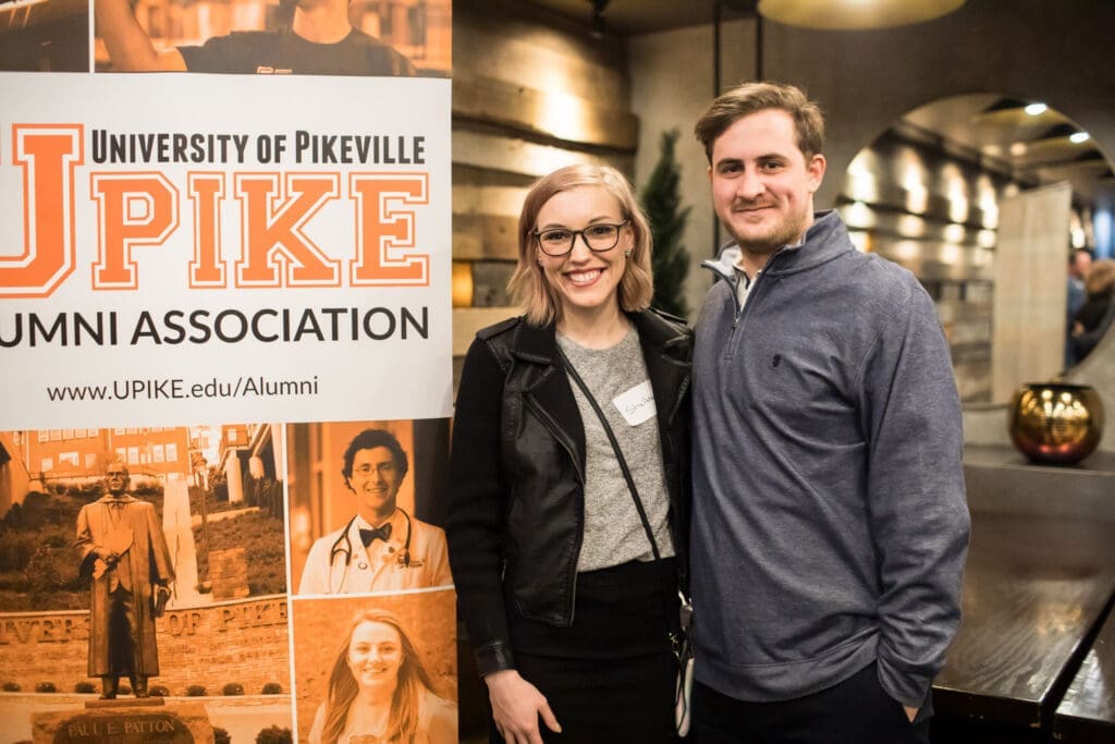 two guests pose in front of UPIKE banner