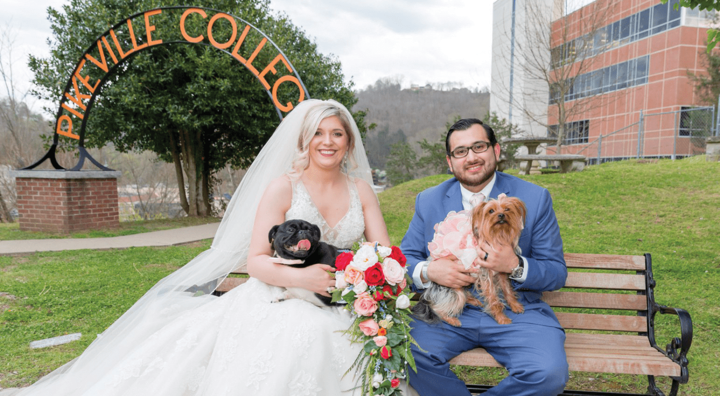 A bride and groom pose with their two puppies on UPIKE's Allara Courtyard.