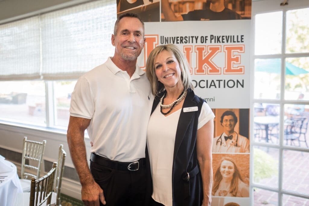 two event attendees pose for a photo in front of the UPIKE banner