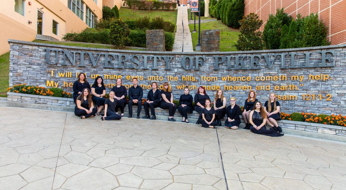 university choir in front of ֱ sign