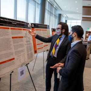 KYCOM student presenting their research poster to a fellow student.