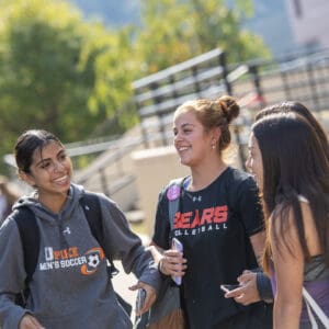 Students smiling while talking on the pedway on campus.