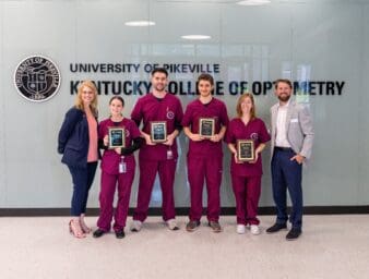 KYCO Dean Reeder posing with the four scholarship winners and representative from National Vision.