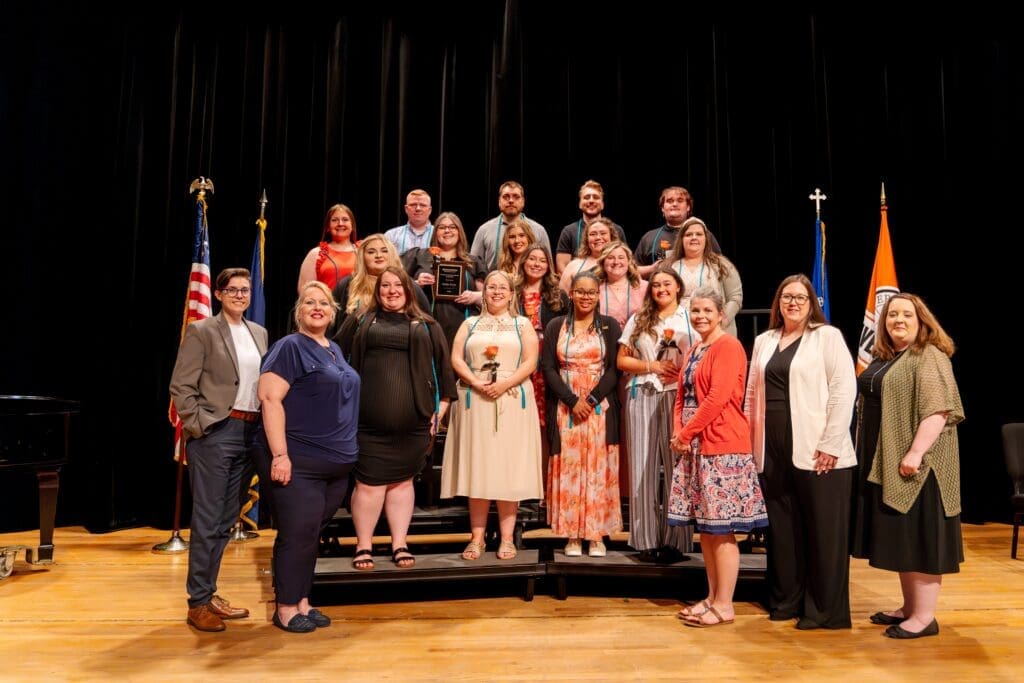 Social Work students joined on stage by faculty at the pinning ceremony.