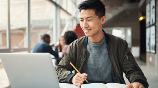 Young man seated in front of a laptop.