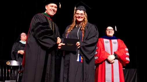 New graduate, Haley McKinney accepting her diploma from UPIKE President Burton Webb