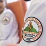 Close-up photo of the KYCOM patch on a white lab coat.