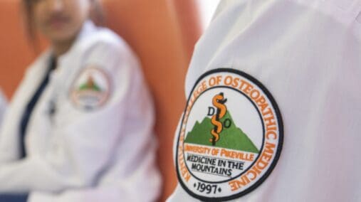 Close-up photo of the KYCOM patch on a white lab coat.