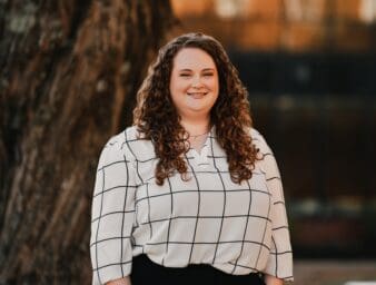 Kate Hensley outside on campus standing in front of a tree.