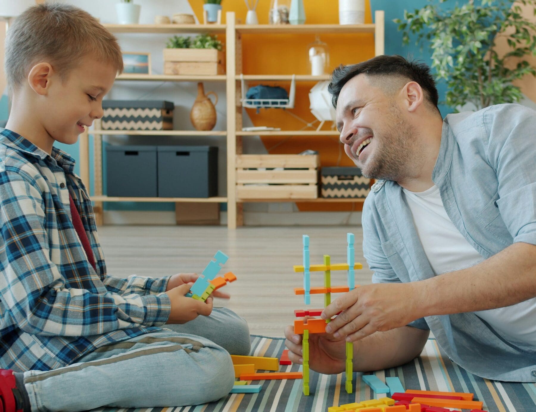 Man and boy sitting on the ground playing with a toy together